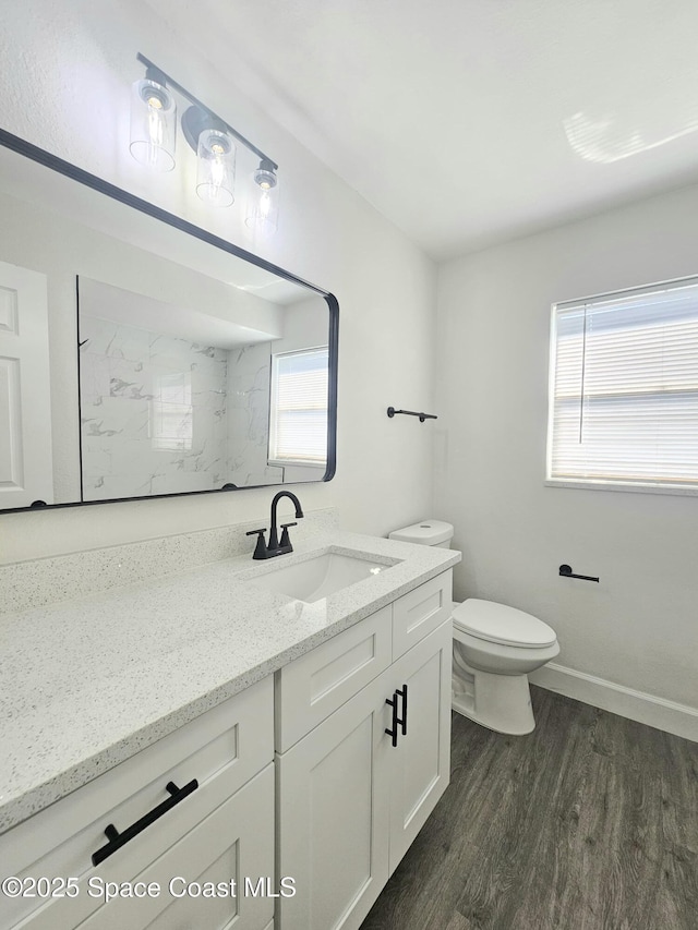 bathroom featuring wood-type flooring, toilet, vanity, and a wealth of natural light