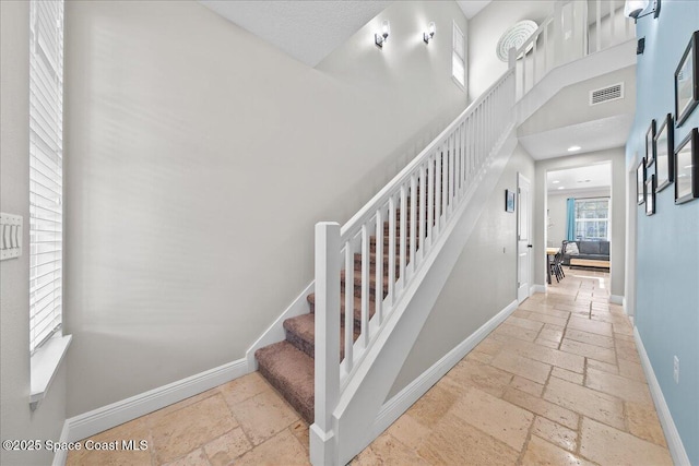 stairway featuring a towering ceiling