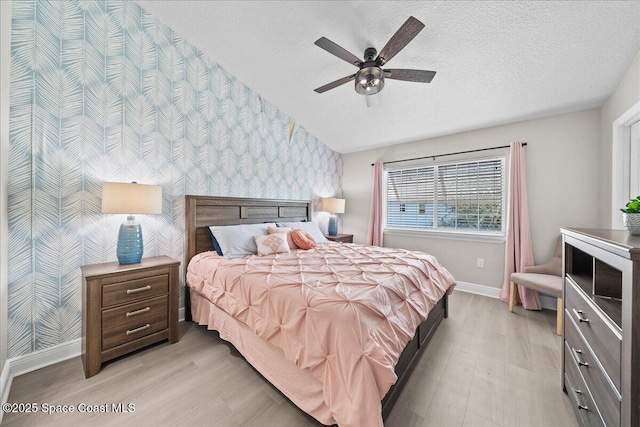 bedroom with ceiling fan, a textured ceiling, and light wood-type flooring