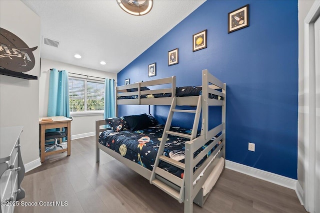 bedroom with hardwood / wood-style flooring, lofted ceiling, and a textured ceiling