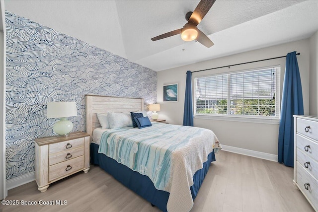 bedroom featuring ceiling fan, lofted ceiling, light hardwood / wood-style floors, and a textured ceiling