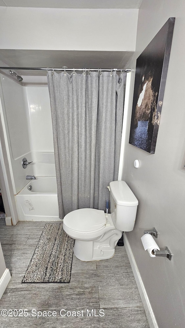 bathroom featuring shower / tub combo with curtain, hardwood / wood-style floors, and toilet