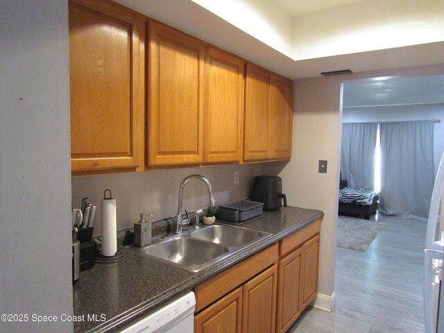 kitchen with white dishwasher, sink, and light wood-type flooring