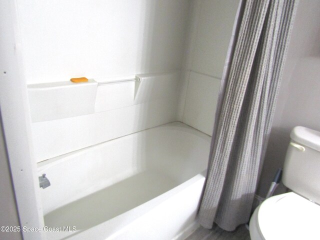 bathroom with shower / bathtub combination with curtain and toilet