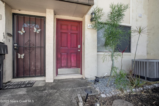 entrance to property featuring central air condition unit and stucco siding