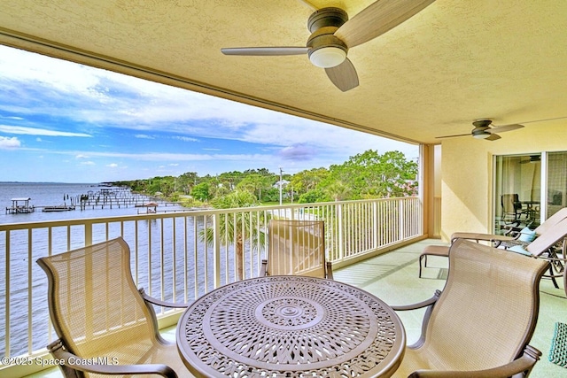 balcony featuring a water view and a ceiling fan