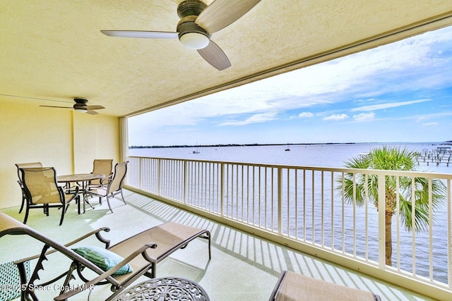 balcony featuring a water view and ceiling fan