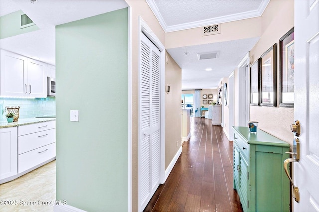 hallway featuring crown molding, light hardwood / wood-style floors, and a textured ceiling