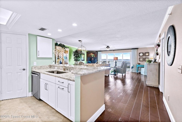 kitchen with sink, white cabinetry, light stone counters, hanging light fixtures, and kitchen peninsula