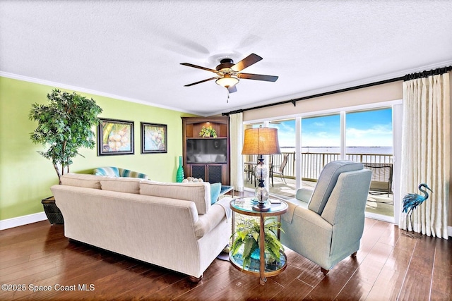 living room featuring dark wood-type flooring, ceiling fan, ornamental molding, and a textured ceiling