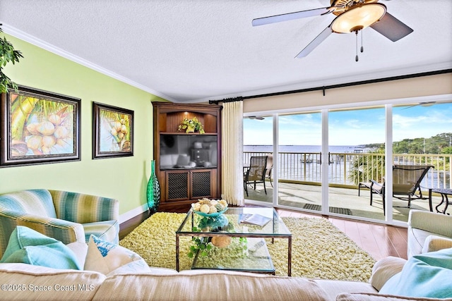 living room with ornamental molding, wood-type flooring, ceiling fan, and a textured ceiling