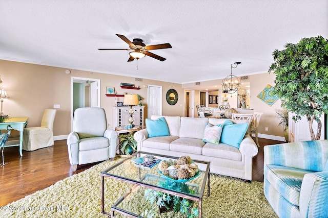 living area with a textured ceiling, ceiling fan with notable chandelier, wood finished floors, baseboards, and crown molding