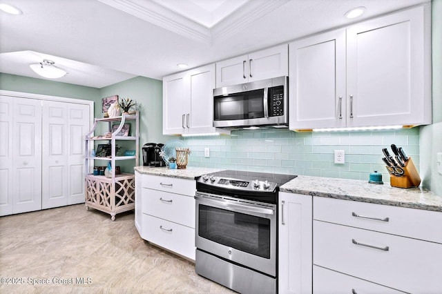 kitchen with stainless steel appliances, white cabinets, backsplash, light stone countertops, and crown molding