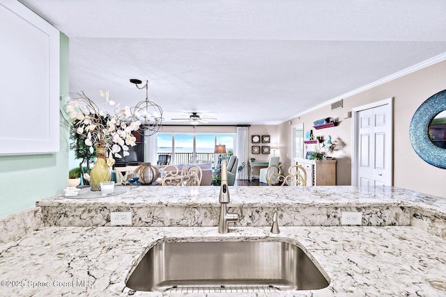 kitchen featuring ornamental molding, light stone countertops, sink, and a chandelier