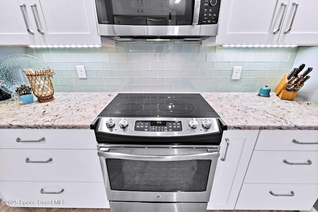 kitchen with appliances with stainless steel finishes, white cabinets, backsplash, and light stone counters