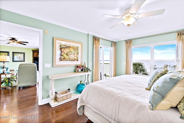 bedroom featuring dark wood-type flooring, ornamental molding, ceiling fan, and a water view