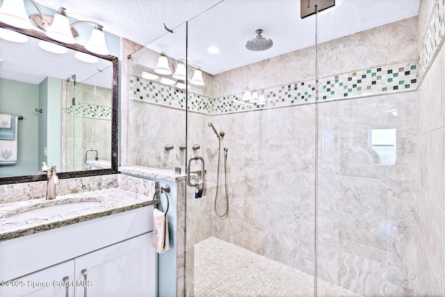 bathroom with vanity, a shower with shower door, and a textured ceiling