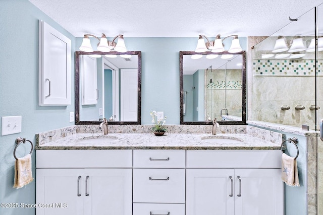 bathroom with a shower with door, vanity, and a textured ceiling