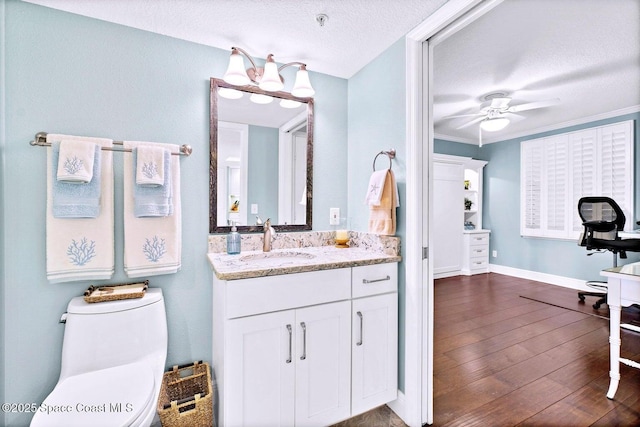 bathroom featuring vanity, wood-type flooring, a textured ceiling, ceiling fan with notable chandelier, and toilet