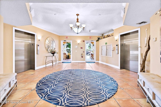 tiled foyer entrance with a notable chandelier, a textured ceiling, ornamental molding, and elevator