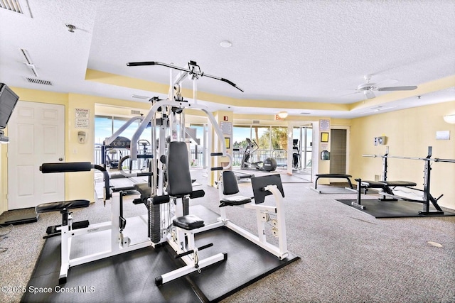 gym featuring a raised ceiling, visible vents, and a textured ceiling