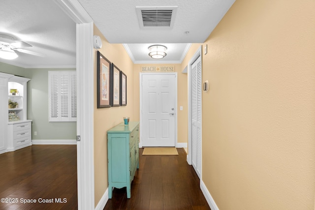 hall with baseboards, dark wood finished floors, visible vents, and crown molding