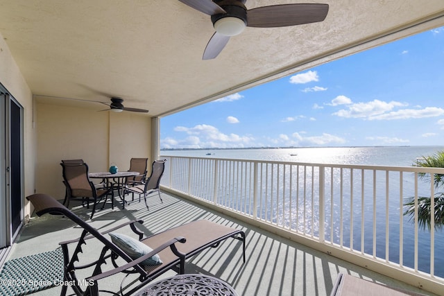 balcony with a ceiling fan, a sunroom, and a water view