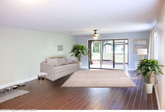 living room featuring dark wood-type flooring and ceiling fan