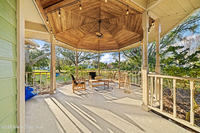 view of patio featuring an outdoor stone fireplace, a gazebo, and ceiling fan