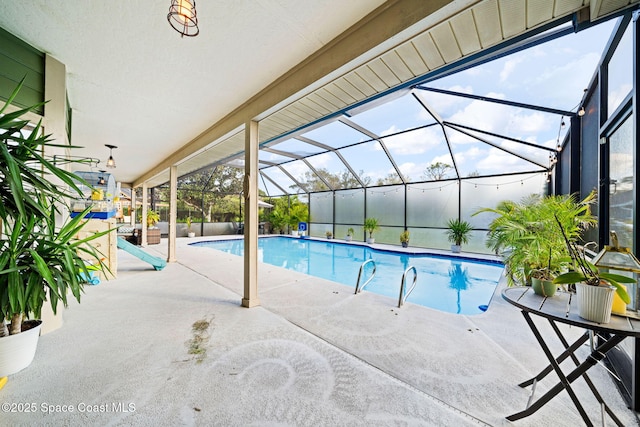 view of swimming pool featuring glass enclosure and a patio area