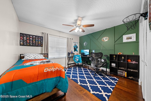 bedroom featuring ceiling fan, dark hardwood / wood-style floors, and a textured ceiling