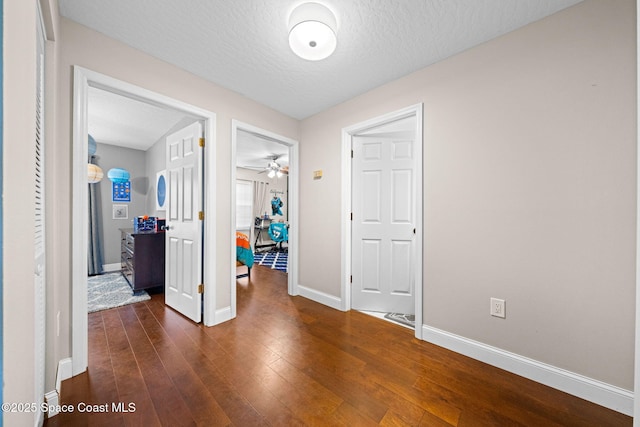 hallway featuring a textured ceiling and dark hardwood / wood-style flooring