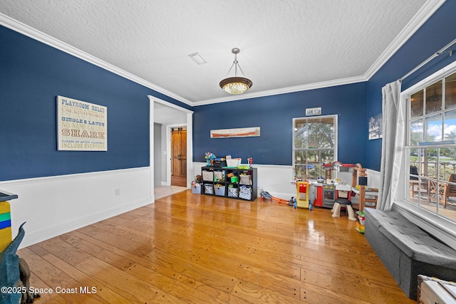 playroom featuring hardwood / wood-style flooring, crown molding, and a textured ceiling