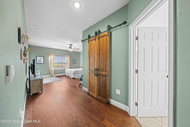 bedroom with hardwood / wood-style flooring, a barn door, and a textured ceiling