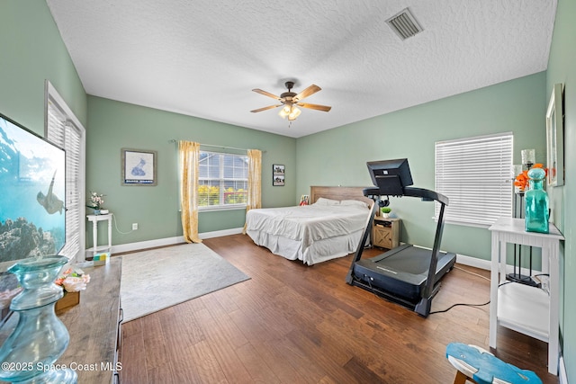 bedroom featuring ceiling fan, a textured ceiling, and dark hardwood / wood-style flooring