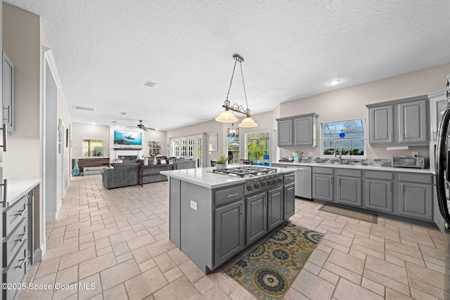 kitchen featuring pendant lighting, sink, gray cabinets, appliances with stainless steel finishes, and a kitchen island