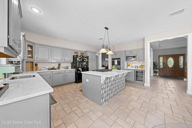 kitchen featuring wine cooler, stainless steel appliances, a center island, and gray cabinetry