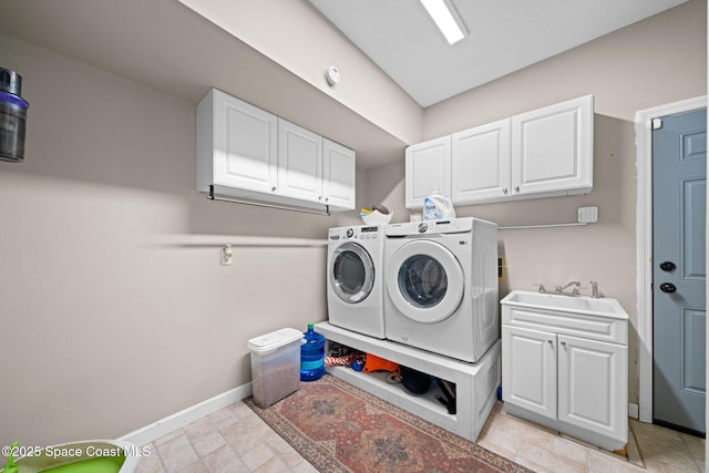 clothes washing area with sink, washer and clothes dryer, and cabinets