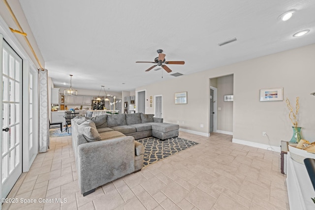 living room featuring ceiling fan with notable chandelier and a textured ceiling