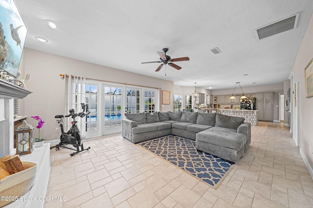 living room with ceiling fan and a textured ceiling