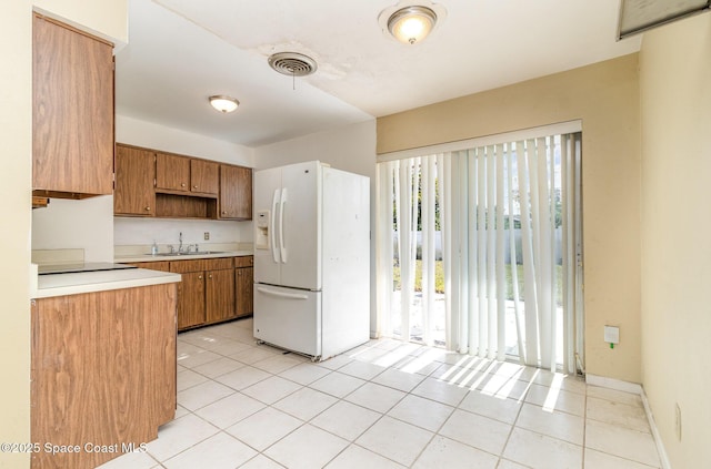 kitchen with light tile patterned floors, sink, and white fridge with ice dispenser