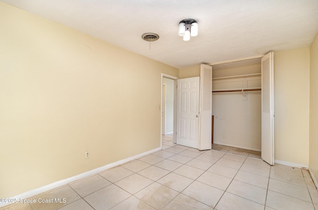 unfurnished bedroom with light tile patterned flooring and a closet