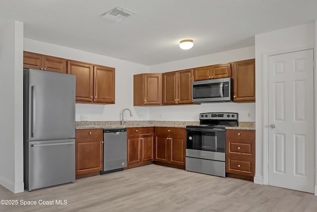 282 Hollywood Blvd, Melbourne, FL 32904 - kitchen with light stone countertops, stainless steel appliances, sink, and light wood-type flooring