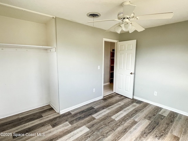 unfurnished bedroom featuring ceiling fan, dark hardwood / wood-style flooring, and a closet