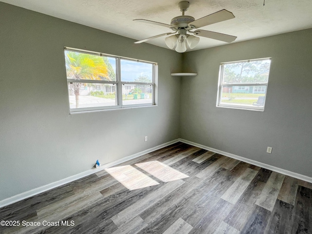 unfurnished room with a textured ceiling, a wealth of natural light, dark hardwood / wood-style floors, and ceiling fan