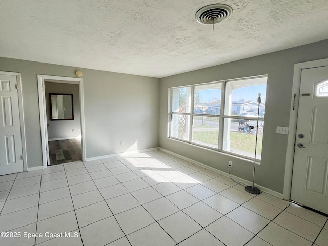 entryway with light tile patterned flooring and a textured ceiling