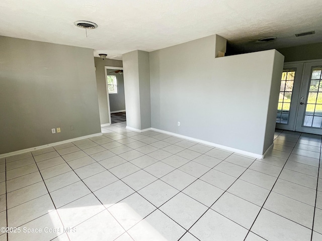 unfurnished room featuring light tile patterned floors, a textured ceiling, and french doors