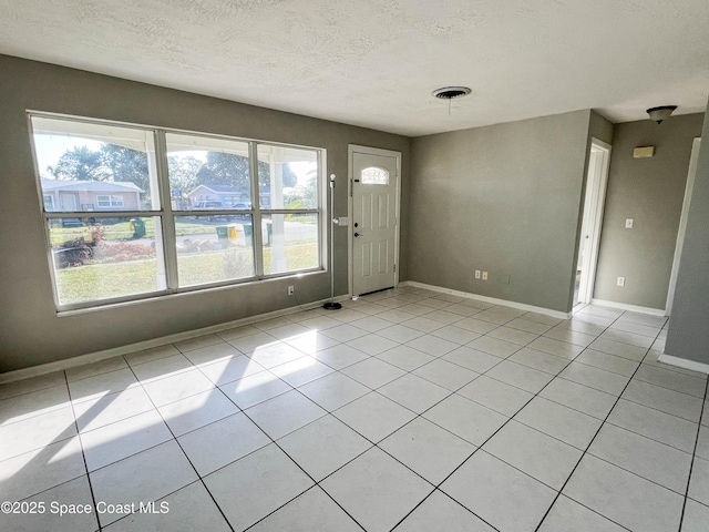 empty room with light tile patterned floors and a textured ceiling