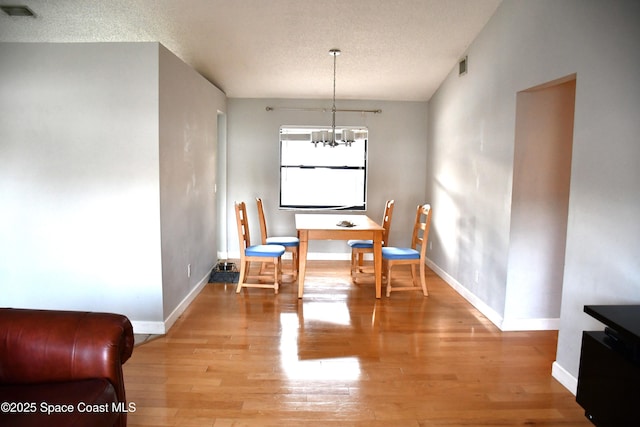 dining space featuring a textured ceiling, a chandelier, and light wood-type flooring