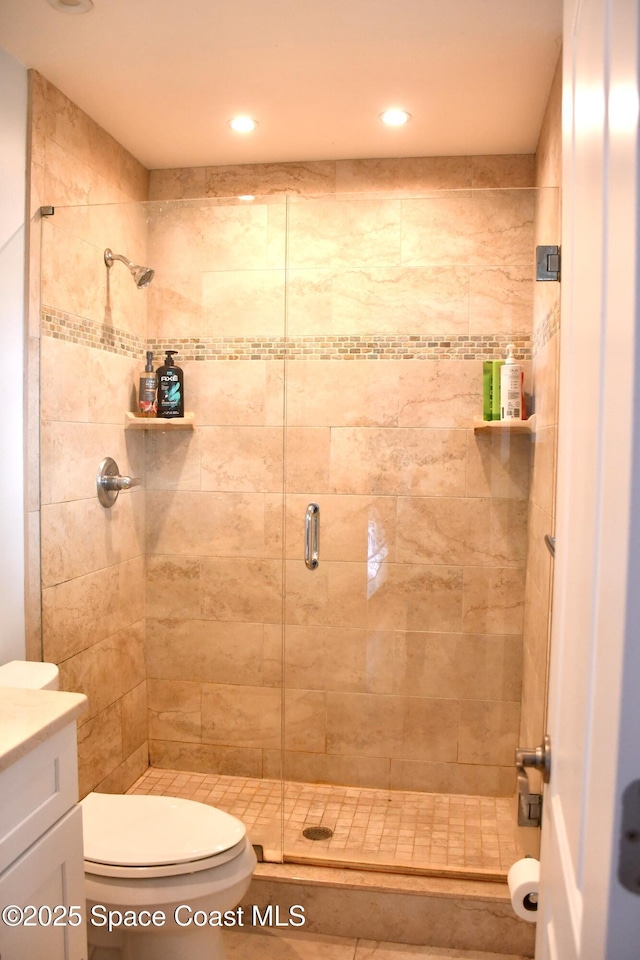 bathroom featuring vanity, a shower with shower door, and toilet